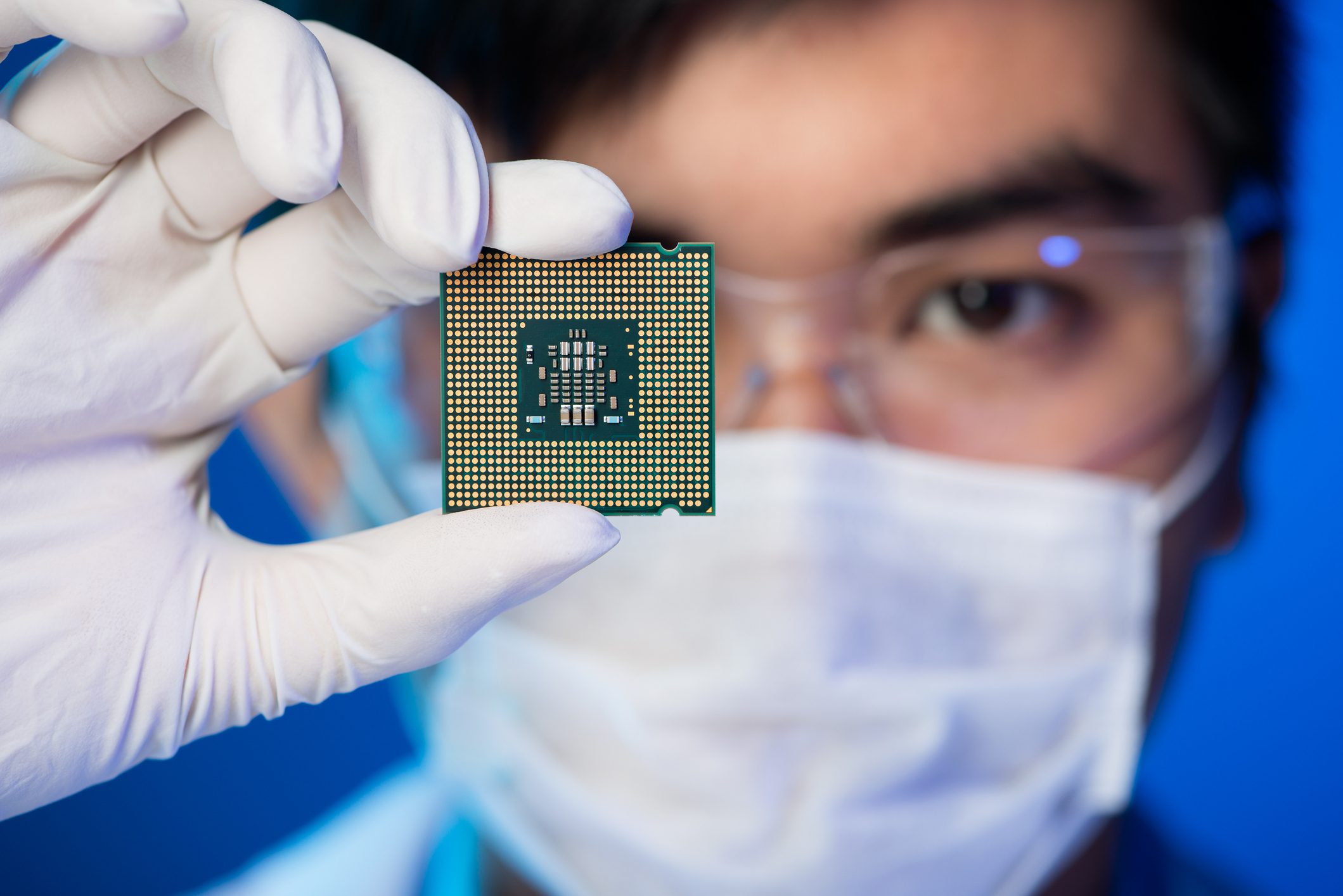 Scientist holding microchip with gloved hand.