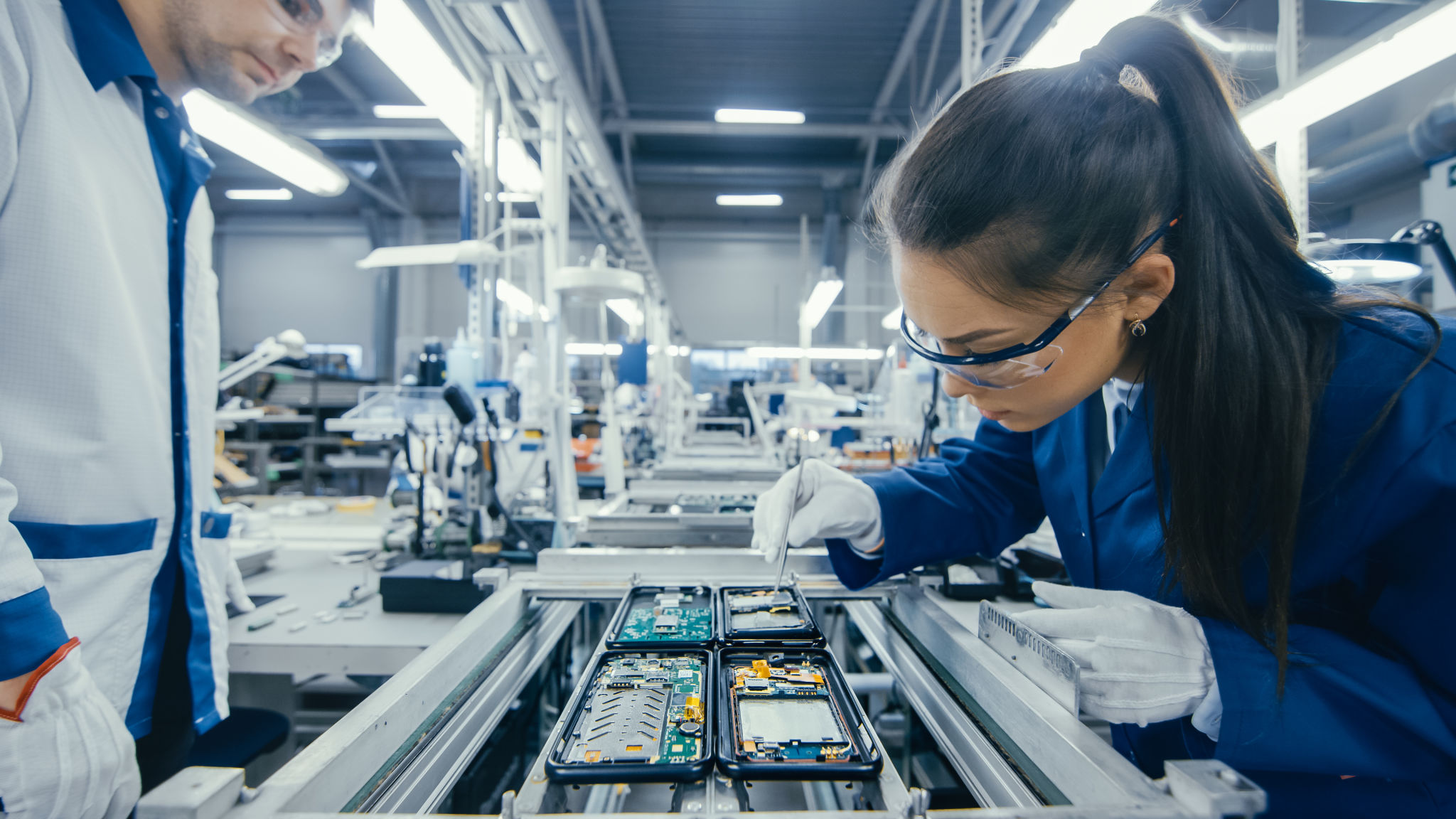 Workers inspecting electronics on assembly line.